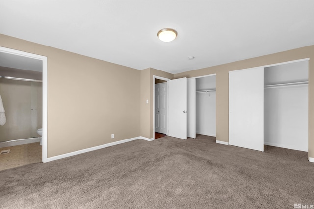 unfurnished bedroom with ensuite bathroom, carpet, baseboards, and two closets