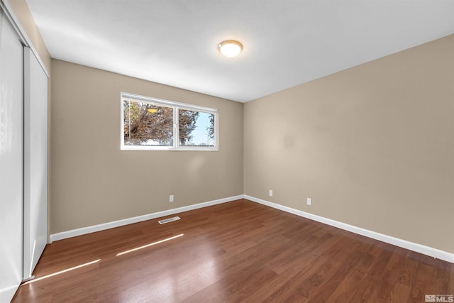 unfurnished bedroom with visible vents, baseboards, a closet, and wood finished floors