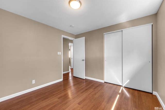 unfurnished bedroom with a closet, baseboards, and wood finished floors