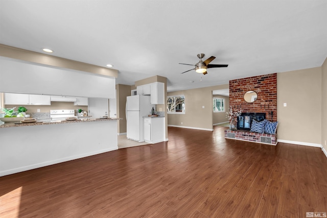 unfurnished living room featuring a ceiling fan, a brick fireplace, wood finished floors, and baseboards