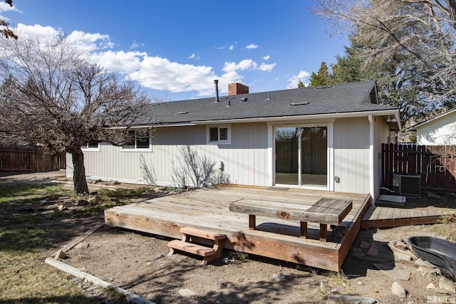 back of property featuring a wooden deck, fence, roof with shingles, and a chimney