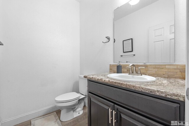 bathroom with backsplash, baseboards, toilet, and vanity