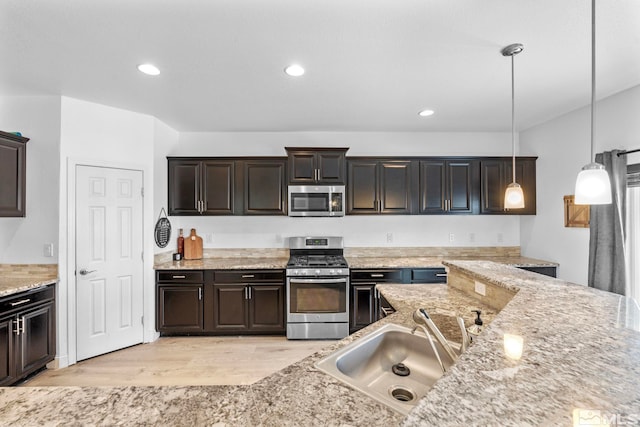 kitchen featuring pendant lighting, recessed lighting, appliances with stainless steel finishes, light wood-style floors, and a sink