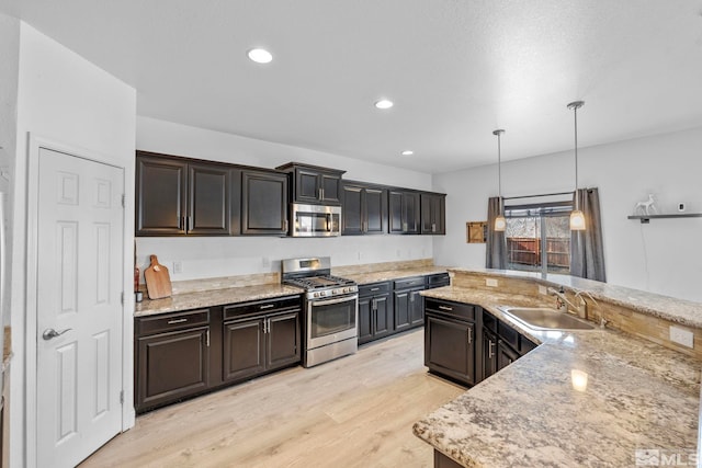 kitchen with decorative light fixtures, recessed lighting, light wood-style flooring, stainless steel appliances, and a sink