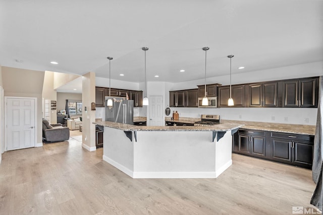 kitchen featuring dark brown cabinetry, a breakfast bar, light wood-type flooring, light stone counters, and appliances with stainless steel finishes