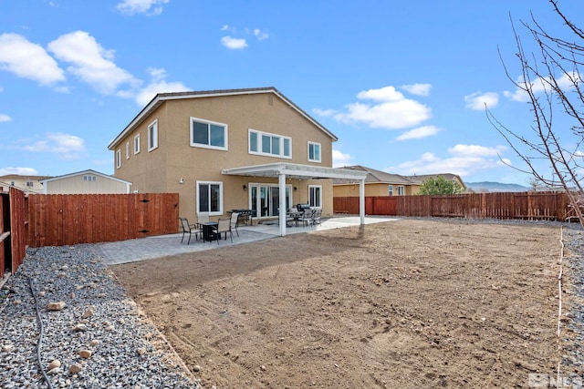 back of house with stucco siding, a patio area, a fenced backyard, and a pergola