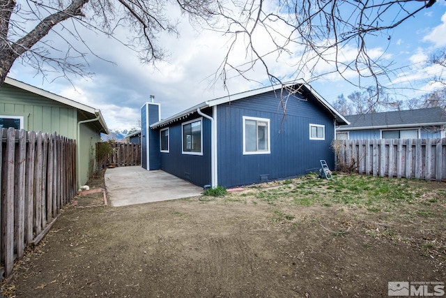 rear view of house featuring a fenced backyard, a chimney, and a patio area