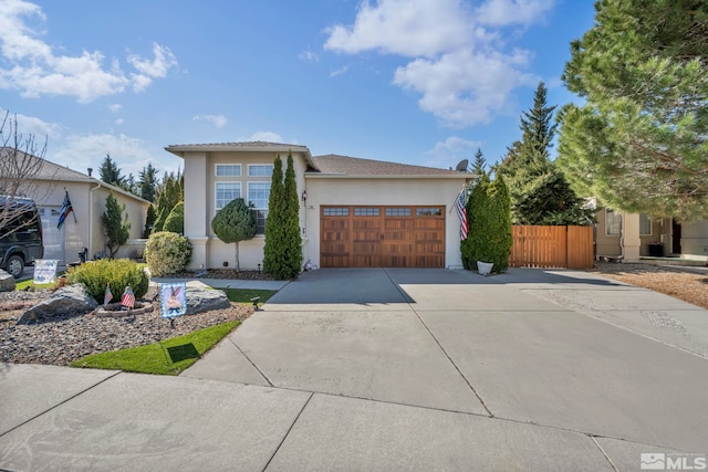 view of front of property with fence, a garage, driveway, and stucco siding