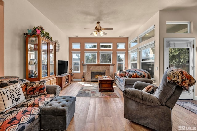 living room featuring ceiling fan, hardwood / wood-style floors, and a tiled fireplace