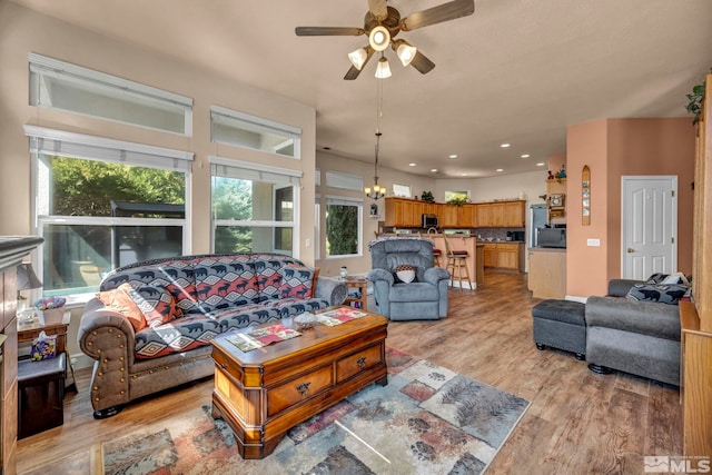 living room with ceiling fan with notable chandelier, plenty of natural light, light wood-style floors, and recessed lighting