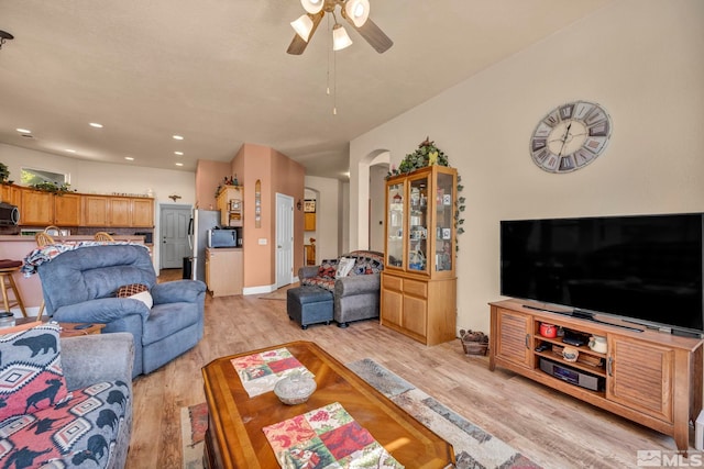 living room featuring light wood finished floors, baseboards, ceiling fan, recessed lighting, and arched walkways