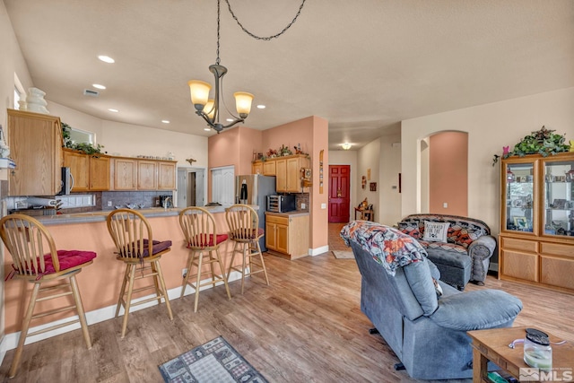 living area featuring visible vents, light wood-style flooring, recessed lighting, arched walkways, and a chandelier