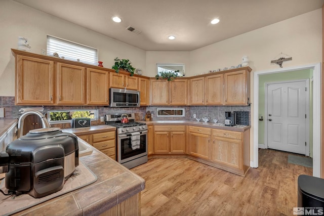 kitchen featuring tile counters, light wood-style floors, visible vents, and stainless steel appliances