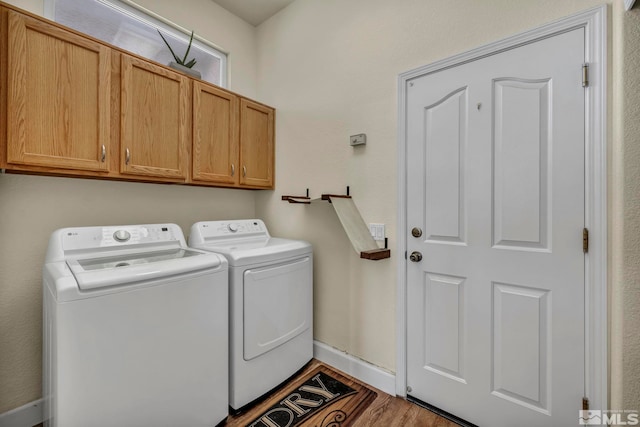 laundry room featuring washer and dryer, baseboards, cabinet space, and wood finished floors