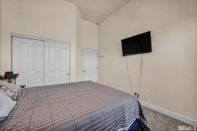 carpeted bedroom with a closet, baseboards, and high vaulted ceiling