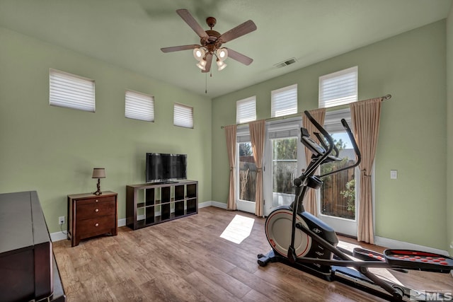 workout room featuring visible vents, a ceiling fan, baseboards, and wood finished floors