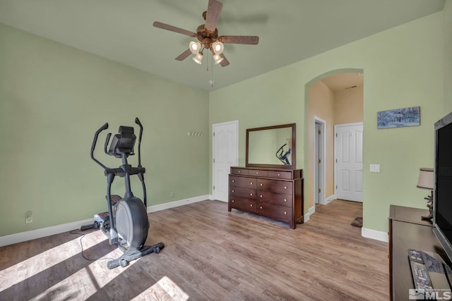 workout area featuring ceiling fan, wood finished floors, arched walkways, and baseboards