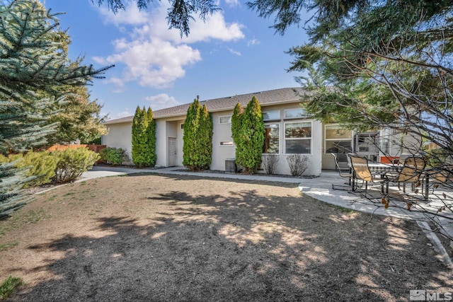 view of front of house with a patio area, stucco siding, and fence