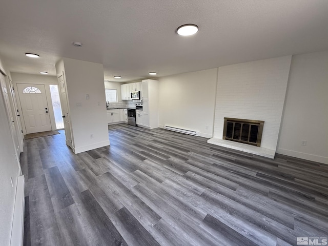 unfurnished living room with dark wood-style floors, a fireplace, baseboards, and baseboard heating