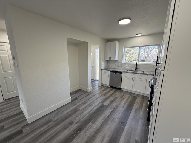 kitchen with backsplash, dishwasher, white cabinetry, and baseboards