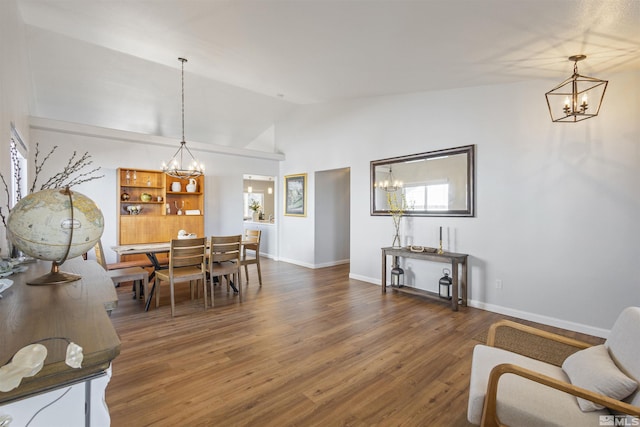 dining area featuring a notable chandelier, baseboards, lofted ceiling, and wood finished floors