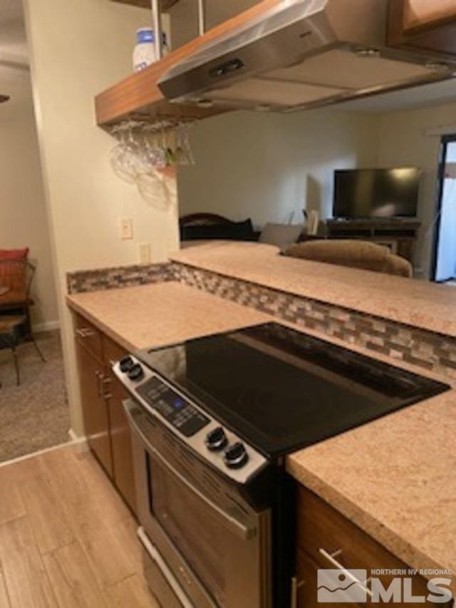 kitchen featuring under cabinet range hood, light wood-style floors, light countertops, and stainless steel range with electric cooktop