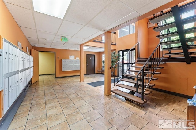 stairway with tile patterned floors, a drop ceiling, and mail area