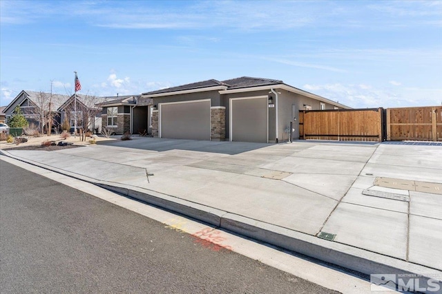 view of front of home featuring concrete driveway, an attached garage, fence, and stucco siding