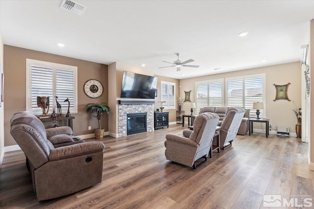 living room with a fireplace, wood finished floors, visible vents, and baseboards