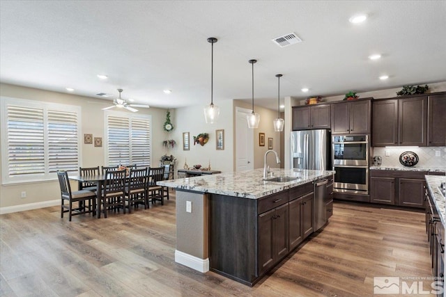 kitchen with dark brown cabinetry, visible vents, stainless steel appliances, and a sink