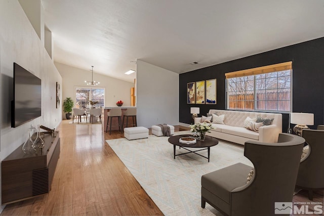 living area featuring lofted ceiling, a notable chandelier, and hardwood / wood-style floors