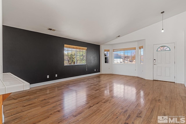 unfurnished living room featuring baseboards, lofted ceiling, and wood finished floors