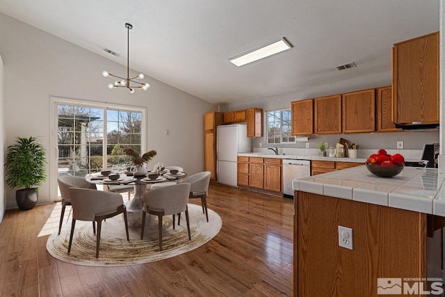 kitchen with dishwasher, brown cabinetry, visible vents, and freestanding refrigerator