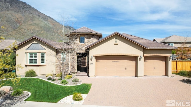 view of front of home featuring stucco siding, decorative driveway, stone siding, fence, and a garage