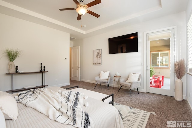 carpeted bedroom with a tray ceiling, baseboards, and ceiling fan