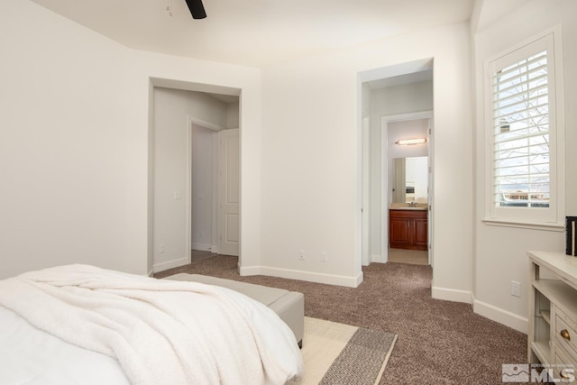 carpeted bedroom with baseboards, ensuite bath, and a ceiling fan