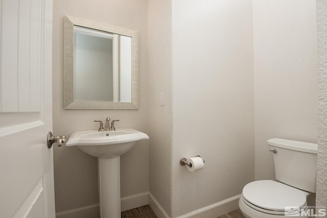 bathroom featuring a sink, toilet, baseboards, and wood finished floors