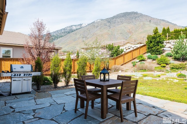 view of patio / terrace with outdoor dining space, fence, a mountain view, and grilling area