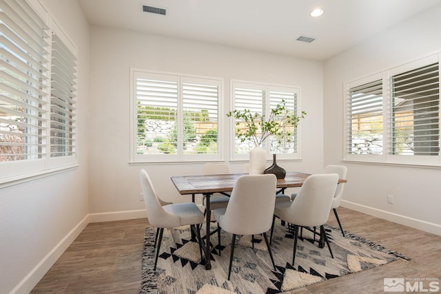 dining room featuring wood finished floors, visible vents, and a wealth of natural light