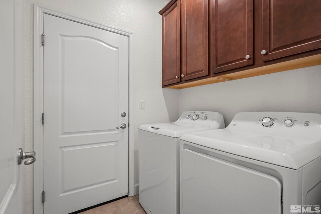 laundry room with cabinet space, light tile patterned flooring, and washer and clothes dryer