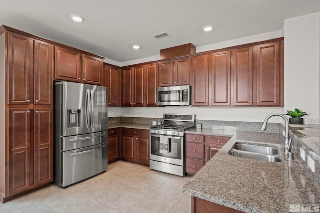 kitchen featuring light stone counters, visible vents, light tile patterned flooring, a sink, and appliances with stainless steel finishes