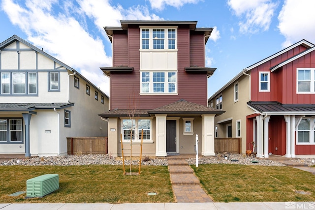 view of front facade with a front yard, fence, and roof with shingles