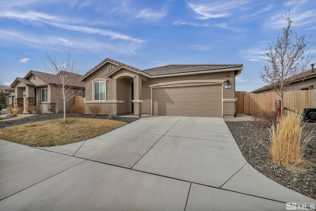 view of front of property featuring stucco siding, driveway, fence, a garage, and a tiled roof