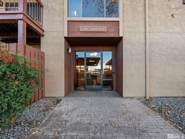 property entrance featuring stucco siding and fence