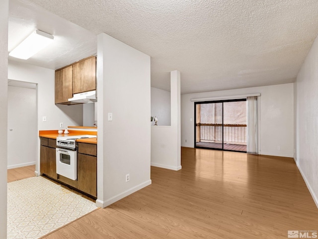 kitchen featuring baseboards, white range with electric cooktop, light wood-style flooring, light countertops, and under cabinet range hood