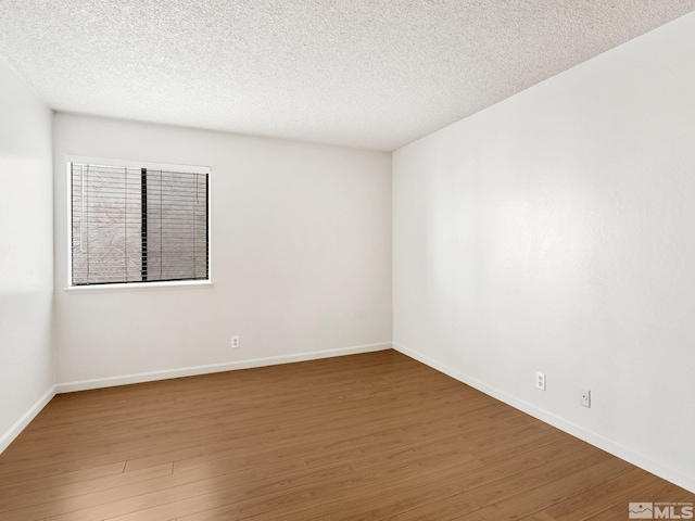 spare room with baseboards, a textured ceiling, and wood finished floors