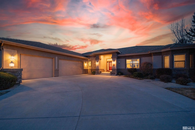 view of front of home with concrete driveway, an attached garage, stone siding, and stucco siding