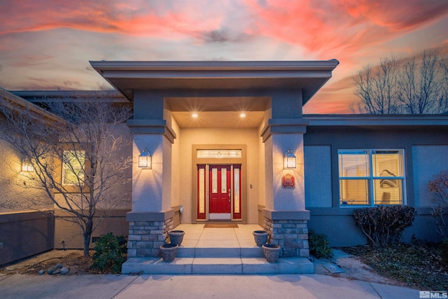 exterior entry at dusk featuring stucco siding