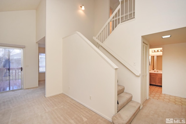 staircase with carpet flooring, a high ceiling, and baseboards