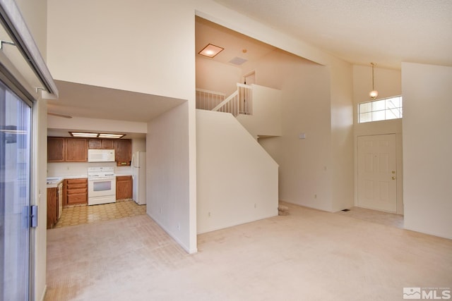 kitchen with white appliances, high vaulted ceiling, brown cabinets, and light carpet